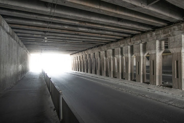 Empty old concrete car tunnel with light at the end.