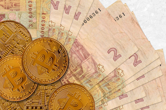2 Ukrainian hryvnias bills and golden bitcoins. Cryptocurrency investment concept. Crypto mining or trading