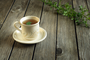 Mint tea in a mug on a table made of wooden boards. Rustic vintage style. Copy space for text. Selective focus