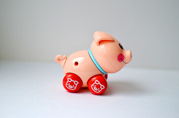 A very small plastic mechanical pink pig toy. Wind-up toy-pig on a white background.