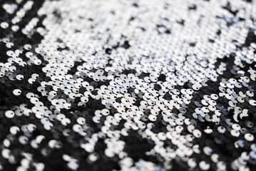 Sequin fabric texture. Shiny silver sparkling background. Clothing piece of glitter metallic for a glamorous party, celebration. Close-up.