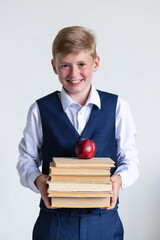 Portrait of a happy schoolboy with a stack of books on which an apple lies in his hands on a white background. The guy gets knowledge, secondary education. Back to school concept