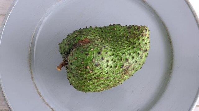 One soursop graviola, exotic, tropical fruit Guanabana on plate, Rotating. Food background