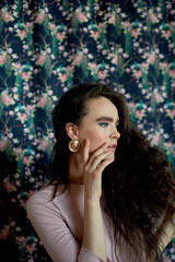 Portrait of a beautiful girl with long curly hair, natural thick eyebrows. In a pink dress.Natural...