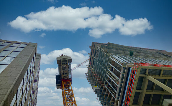 A view of a tall building under construction against a bright. blue. sky. High quality photo
