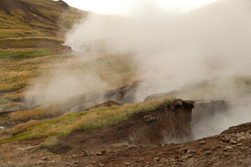 Steam emanates from cracks on a volcanic spring creates a misty landscape in the mountains of Iceland