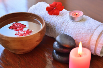 Obraz na płótnie Canvas Spa and beauty salon background scene with a towel, wooden bowl, candle, and stone indoor on wooden desk. Wellness and health care concept. Close up, selective focus