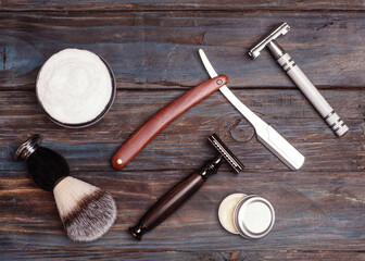 Razors, brush, balsam and foam on a wood background.