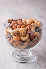 Glass bowl full of mixed nuts over a wooden background. Peanuts, brazilian nuts, cashew nuts, baru nuts and almonds