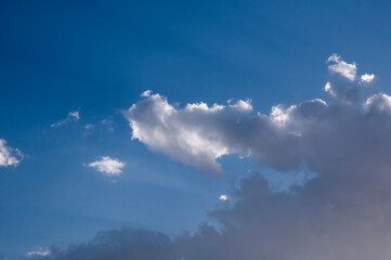 Obraz premium Clouds in the blue sky. Sunny day. Clouds floating across the sky. The clouds are illuminated by the sun's rays.