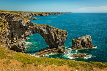 Fototapeta na wymiar The natural arch know as the Green Bridge of Wales together with surrounding stacks on the Pembrokeshire coast, near Castlemartin in early summer