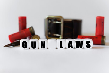 Against the background of cartridges and a military belt, cubes with the inscription - GUN LAWS