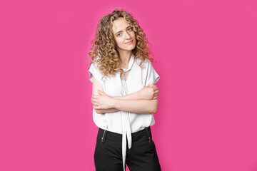 A beautiful young woman stands with crossed arms.