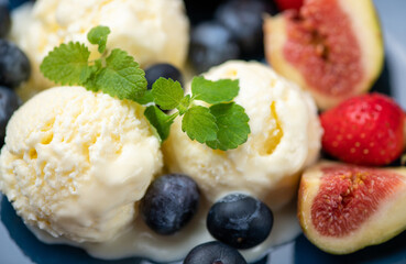 three scoops of ice cream, figs, blueberries, and a mint leaf on a blue plate