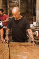 Hombre carpintero en taller revisando madera