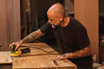 carpintero trabajando con madera y maquina lijadora