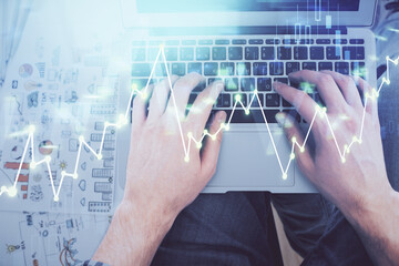 Double exposure of man's hands typing over laptop keyboard and forex chart hologram drawing. Top view. Financial markets concept.