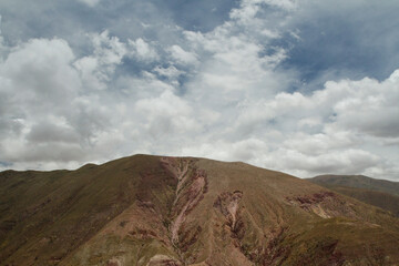 Andes mountain range. Aerial view of the brown mountain peak under a beautiful cloudy sky. 