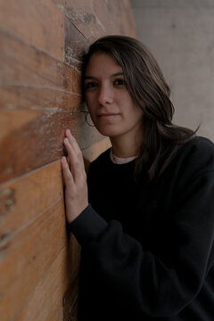 Joven mujer mirando hacia adelante apoyada en pared de madera concept stay home woman covid 19