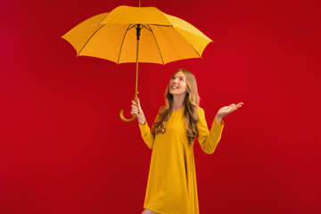 happy young woman with yellow umbrella on red background, autumn concept