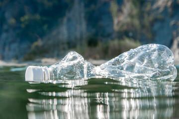 A plastic bottle floats on the water surface by the ocean. Ecology concept.