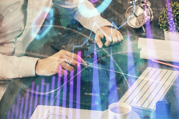 Double exposure of man's hands holding and using a phone and financial graph drawing. Analysis concept.