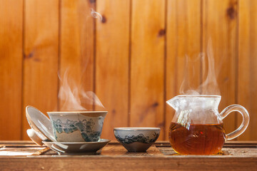 Chinese tea cup and glass kettle  with cloud of vapor on wooden background