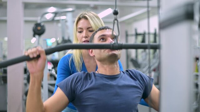 A client of a sports club is engaged under the supervision of a female coach, front view