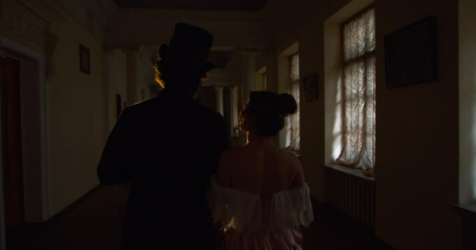 View from the back on a couple from the 18th century walking in the hallway, 4k