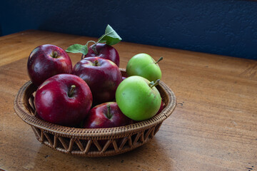 Harvest time - a basket of freshly picked  red and green apples from our orchard sitting on a wood table