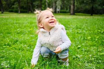 The child is joyful sitting in the grass in the park