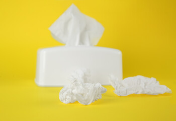 Used paper tissues and white holder on yellow background, closeup
