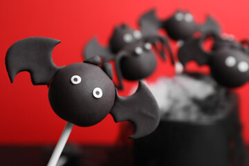 Delicious Halloween themed cake pops on red background, closeup. Space for text