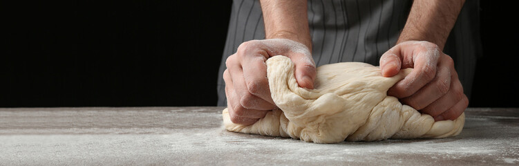 Baker kneading dough at table, closeup. Banner design with space for text