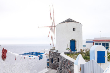 Famous windmill on a cloudy day in Oía, Santorini Island. Copy space.