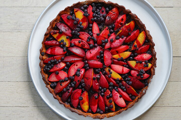 Homemade tart with fresh plumcots and blueberries - obrazy, fototapety, plakaty