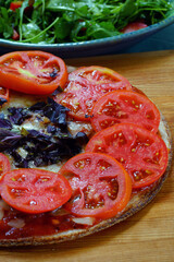 Homemade pizza with fresh sliced tomatoes and purple basil on a cauliflower crust