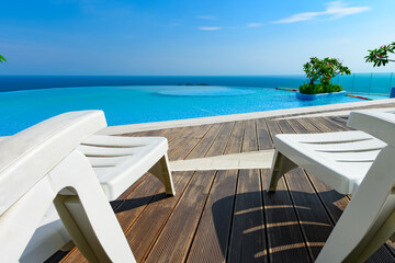 Fototapeta premium sun loungers in front of a swimming pool with the ocean at the far end