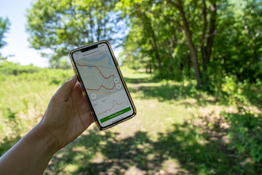 Mankato, Minnesota - June 5, 2020: Hiker uses an AllTrails hiking map app on her phone to navigate the trails in Minneopa State Park