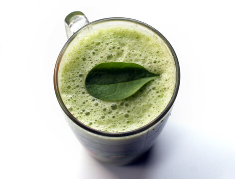 a glass of green cocktail with spinage leaf