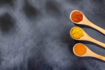 Curry, turmeric and paprika spices in the wooden spoons