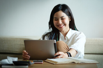 Woman hold with tablet at sit on sofa and use tablet happily at home.