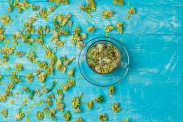Tea in a glass mug with dried herbs top view on a blue wooden background