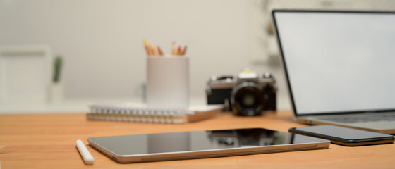 Workspace with digital tablet, laptop, camera, smartphone and stationery on wooden desk