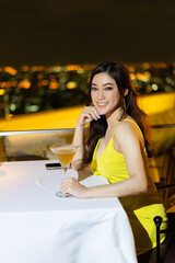 woman in evening dress holding cocktail at restaurant over night city background
