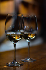 Pair of wine glasses with white wine and reflection of wine barrels. Wine tasting in a wine cellar. Vineyard in Mendoza region, Argentina