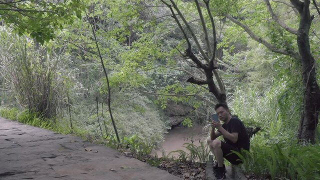 A man is resting and taking pictures in the forest.