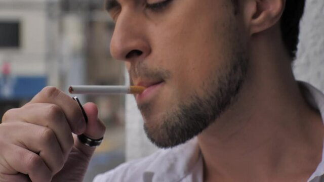 Man lights cigarette and smokes it in slow motion