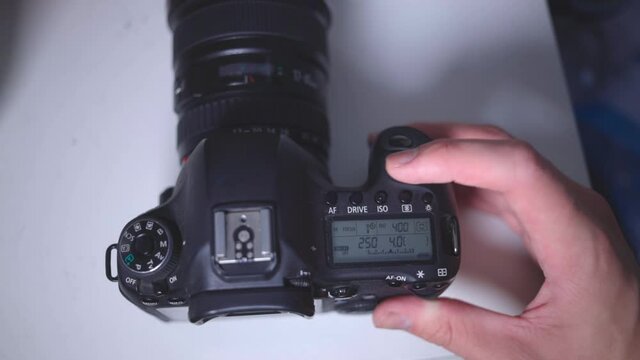 Photographer's Hand Spinning The Main Command Dial Of A DSLR Camera On The Table - overhead shot