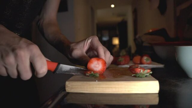 Slicing Strawberry Using Kitchen Knife On A Wooden Chopping Board. - close up shot